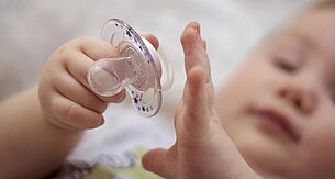 A baby's hand holds a pacifier.