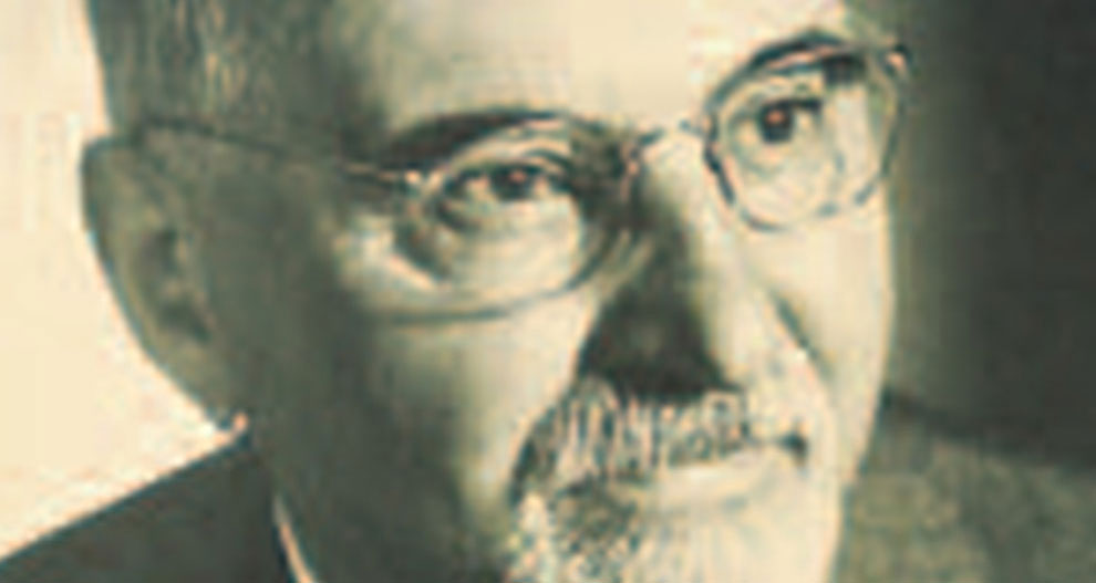 Vīrieša sejas tuvplāns, kurā redzamas acis, deguns un mute ar bārdu un ūsām, viņš valkā brilles.