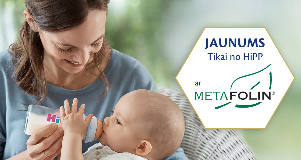 Sieviete baro bērnu ar pudelīti, bet fonā redzama sešstūra formas etiķete, kas reklamē produktu ar tekstu "JAUNUMS Tikai no HiPP ar META FOLIN®".