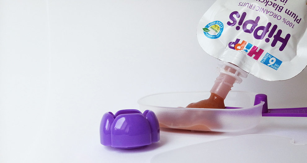 Izspiedēja pudele, no kuras ielej brūnu šķidrumu mazā traukā ar violetu vāku.